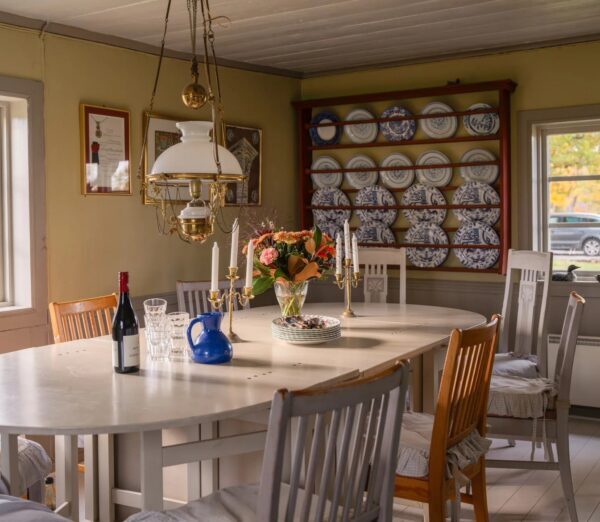 Comedor con mesa gustaviana, vajilla azul y blanca y expositor de platos en casa de campo sueca decoracion rústica